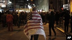 A man carries an American flag while walking to join a crowd gathered to celebrate the death of Osama bin Laden at the construction site at Ground Zero in New York, May 2, 2011.