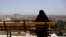 A woman sits on a bench overlooking Aleppo's ancient citadel and the old city, Syria April 13, 2019. 