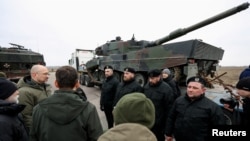 资料照片：乌克兰总理什米加尔与波兰总理莫拉维茨基与波兰军人交谈，身旁是从波兰运抵乌克兰某地的第一批豹2坦克。(2023年2月24日)