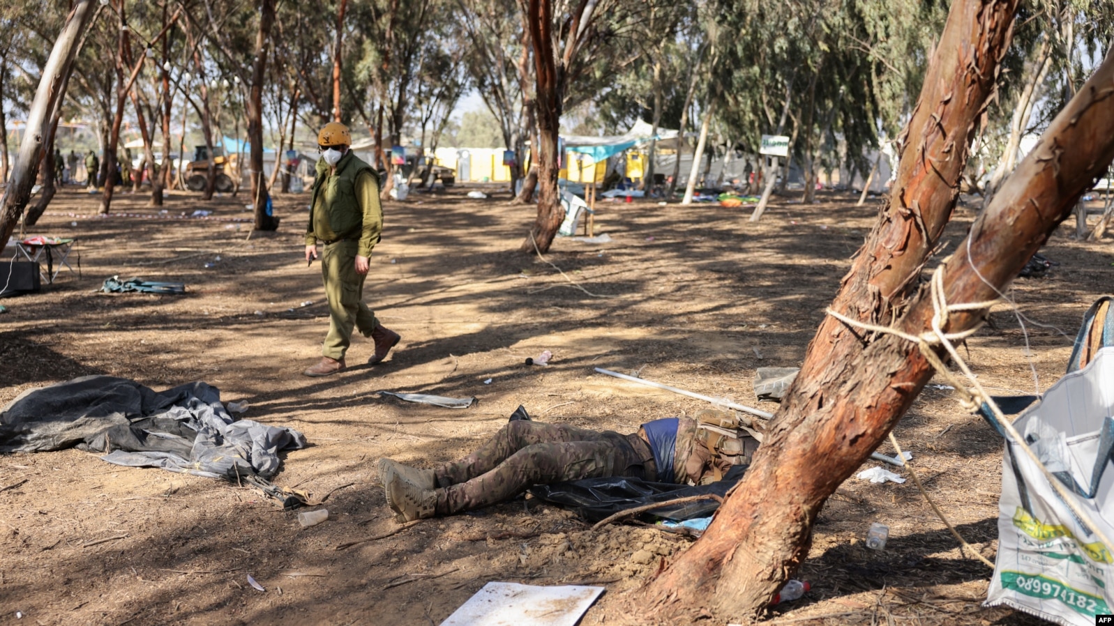 EDITORS NOTE: Graphic content / An Israeli soldier walks past the body of a Palestinian gunman during a search at the site of the weekend attack by Palestinian militants on the Supernova Desert Music Festival on October 12, 2023. (Photo by Menahem KAHANA / AFP)