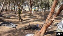 EDITORS NOTE: Graphic content / An Israeli soldier walks past the body of a Palestinian gunman during a search at the site of the weekend attack by Palestinian militants on the Supernova Desert Music Festival on October 12, 2023. (Photo by Menahem KAHANA / AFP)