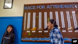 Kanette Yatsattie , 8, left, and classmate Jeremy Candelaria, 10, hang out by a board depicting the race to for best attendance at the school, at Algodones Elementary School in Algodones, New Mexico, Oct. 1, 2024.