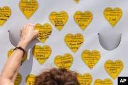 COVID-19 survivors gather at City Hall Park and place stickers representing lost relatives on a wall Aug. 7, 2021, in New York, as part of the largest nationwide day of awareness and action for COVID-19 survivors.