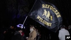 Activists and members of associations defending migrants' rights holding a flag stand next to a banner reading "309 dead on the France UK border since 1999", during a gathering outside the port of Calais, northern France, Nov. 25, 2021.