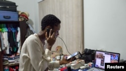 FILE - Illustrator Sena Ahadji speaks to a client on the phone from her house in Accra, Ghana, July 24, 2015. 