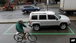 Seorang pengendara sepeda melewat sebuah mobil sewaan yang terparkir di Hoboken, New Jersey, 4 Juni 2012. (Foto: AP/ilustrasi)