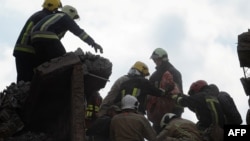 在乌克兰普里卢基(Pryluky)一栋多层住宅楼遭俄军空袭后，救援人员在现场开展搜救行动时，抬着从废墟中寻获的一名儿童的遗体。(2026年10月7日)