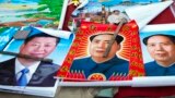 FILE - In this Feb. 5, 2015 file photo, vendors sell posters of Chinese President Xi Jinping, left, and Communist Party founder Mao Zedong, center and right, on a street of Gujiao in northern China's Shanxi province. 