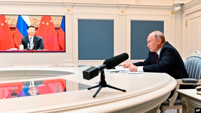 Presiden Rusia Vladimir Putin berbicara dengan Presiden China Xi Jinping (di layar) melalui konferensi video di Moskow, Rusia, Senin, 28 Juni 2021. (Alexei Nikolsky, Sputnik, Kremlin Pool Photo via AP)
