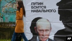 Seorang perempuan melewati poster yang berbunyi "Putin takut pada Navalny" di Kirov, Rusia (16/10/2013). Alexei Navalny adalah pemimpin oposisi dan juga blogger anti korupsi. Rusia memberlakukan UU Blogger tanggal 1/8/2014. 