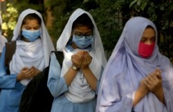 Students wearing face masks to prevent the spread of the coronavirus as they pray upon their arrival at their school, in Karachi, Pakistan, Jan. 18, 2021.