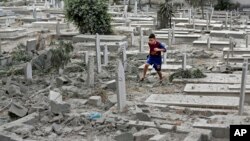 Palestinski dečak na ruševinama groblja u Gazi, koje su bombardovale izraelske vojne snage, 10. avgust 2014.
