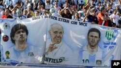 Lionel Messi, à droite, le pape François, au centre, et la légende du football Diego Maradona, à gauche, sur une banderole que brandissent les supporters de l'Argentine lors du dernier match de football de la Copa America entre l'Argentine et le Chili au Stade National de Santiago, au Chili, 4 juillet 2015.