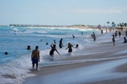 Beachgoers play in the waves on Miami Beach, Florida's famed South Beach, March 22, 2021.