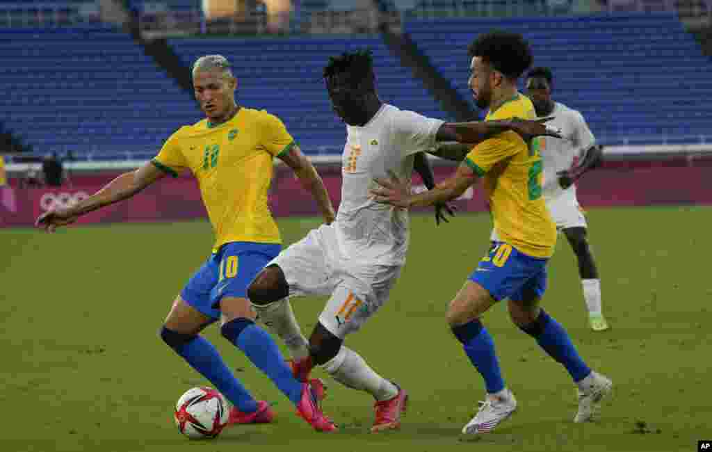 Ivory Coast&#39;s Christian Kouame, center, battles for a ball with Brazil&#39;s Richarlison, left, and Claudinho during a men&#39;s soccer match at the 2020 Summer Olympics, Sunday, July 25, 2021, in Yokohama, Japan. (AP Photo/Kiichiro Sato)