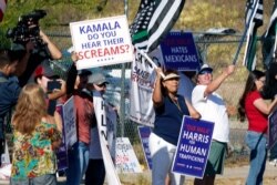 As Vice President Kamala Harris arrives to tour the U.S. Customs and Border Protection Central Processing Center, June 25, 2021, in El Paso, Texas, people rally outside the facility.