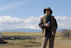 In this photo taken March 20, 2020, cattle rancher Mike Filbin stands on his property in Dufur, Oregon, after herding some cows, and talks about the impact the coronavirus is having on his rural community.