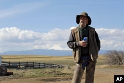 In this photo taken March 20, 2020, cattle rancher Mike Filbin stands on his property in Dufur, Oregon, after herding some cows, and talks about the impact the coronavirus is having on his rural community.