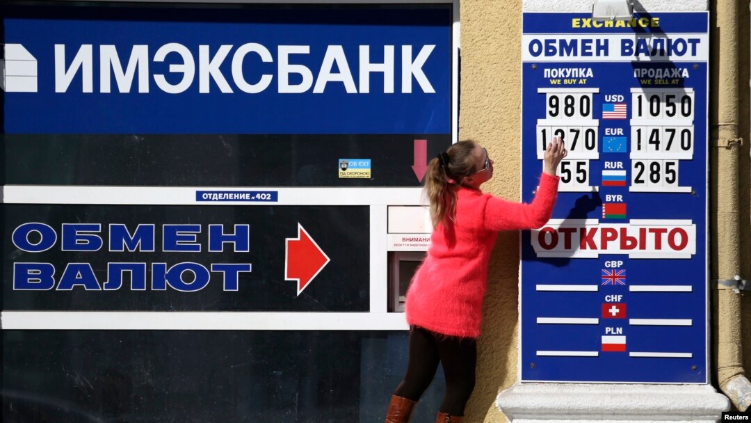 An employee changes rates on a notice board at a currency exchange in Simferopol, March 17, 2014.