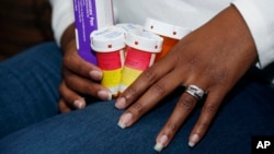 FILE - A patient holds the medications she takes to slow the progression of her multiple sclerosis, Feb. 24, 2015.