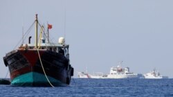FILE - China Coast Guard vessels patrol past a Chinese fishing vessel at the disputed Scarborough Shoal, April 5, 2017.