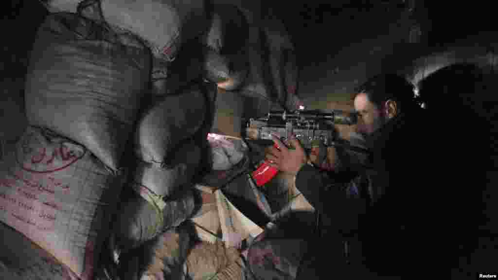 A Syrian army soldier loyal to President Bashar al-Assad points his weapon through piled sandbags at the justice palace in the old city of Aleppo, Feb. 10, 2014.