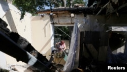FILE - A local resident removes debris inside a house, which locals said was damaged during recent shelling, in the rebel-controlled city of Donetsk, Ukraine, June 17, 2019. 