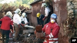 Hungarian rescue workers and fire fighters clean a yard flooded by toxic mud in Kolontar, Hungary, 7 Oct 2010