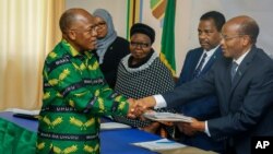 FILE - In this Tuesday, Aug. 25, 2020 file photo, President John Magufuli, left, who seeks a second five-year term, hands over his electoral nomination form to Chairman of the National Electoral Commission (NEC) Judge Semistocles Kaijage, right, in…