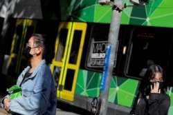 FILE - People wearing face masks walk on Bourke Street after cases of the coronavirus were confirmed in Melbourne, Victoria, Australia, Jan. 29, 2020.