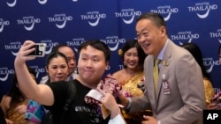 FILE - Chinese tourists take selfies with Thailand's Prime Minister Srettha Thavisin, right, on their arrivals at Suvarnabhumi International Airport in Samut Prakarn province, Thailand, Sept. 25, 2023. 