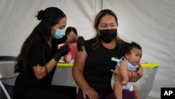 Laura Sanchez, right, holds her 2-month-old son, Lizandro, while receiving the Pfizer COVID-19 vaccine from registered nurse, Noleen Nobleza at a vaccine clinic set up in the parking lot of CalOptima Saturday, Aug. 28, 2021, in Orange, Calif. (AP…