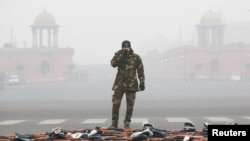 An Indian Air Force soldier drinks tea as he stands guard next to rifles during a break at the rehearsal for the Republic Day parade on a cold winter morning in New Delhi, Dec. 26, 2018. 