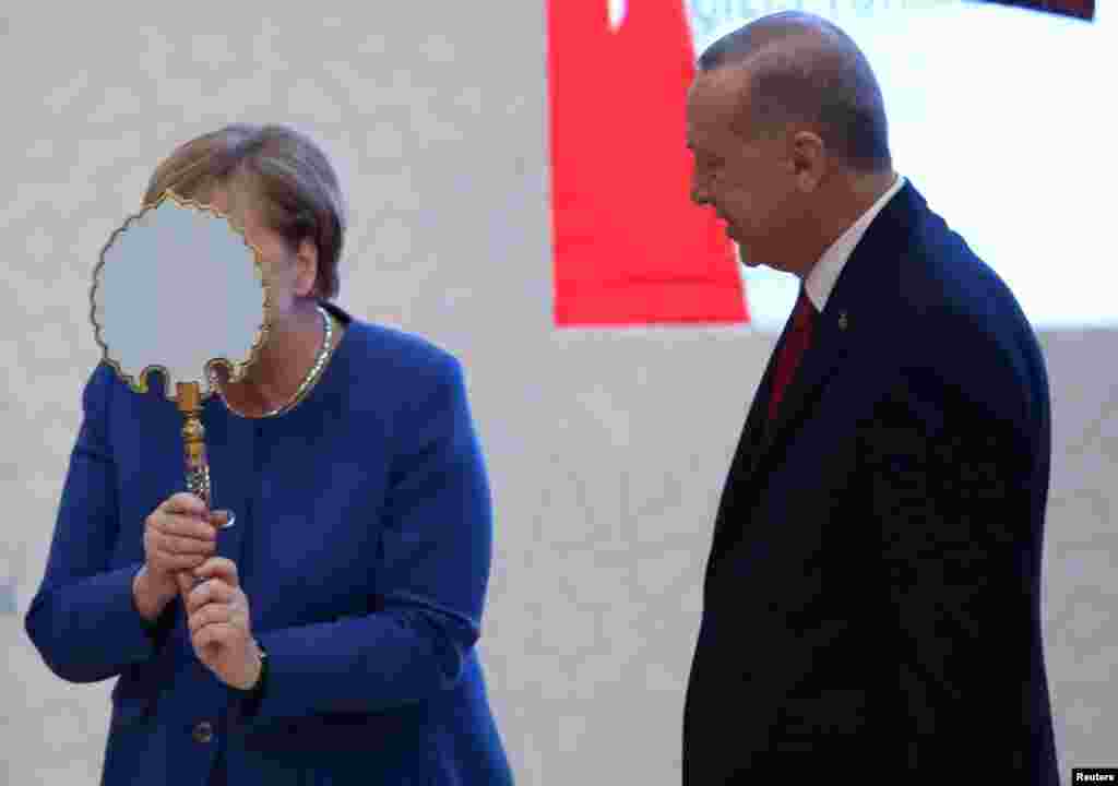 German Chancellor Angela Merkel receives a gift from Turkish President Tayyip Erdogan during the official opening ceremony of Turkish-German University&#39;s new campus in Istanbul, Turkey.