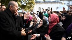 Presiden Turki, Recep Tayyip Erdogan (kiri) menyalami dan berbicara kepada para pendukungnya setelah usai melakukan shalat subuh di masjid Eyup Sultan di Istanbul, Senin pagi (2/11).