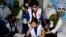 সরকারের নির্দেশ অনুসারে একজন স্বাস্থ্যকর্মী ঢাকায় একটি স্কুল প্রাঙ্গনে এক শিক্ষার্থীকে কোভিড-১৯ টিকা দিচ্ছেন। ১ নভেম্বর, ২০২১। (ছবি-এএফপি/মুনির উজ জামান)