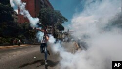 Un manifestante arroja una granada de gas lacrimógeno lanzada por la Policía Nacional Bolivariana durante una manifestación en Caracas, Venezuela, el sábado 8 de abril de 2017.