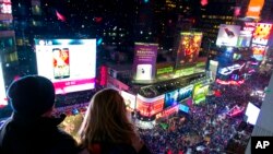 Kenn Magowan, left, Anna Edgerly-Moore, both of New York, look out over Times Square, Wednesday, Jan. 1, 2014.