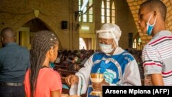 Une catholique reçoit la Sainte Communion à la cathédrale Notre-Dame du Congo à Kinshasa le 16 août 2020 lors de la première messe célébrée depuis le 24 mars, en raison de la pandémie COVID-19.