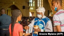 Une catholique reçoit la Sainte Communion à la cathédrale Notre-Dame du Congo à Kinshasa le 16 août 2020 lors de la première messe célébrée depuis le 24 mars, en raison de la pandémie COVID-19.