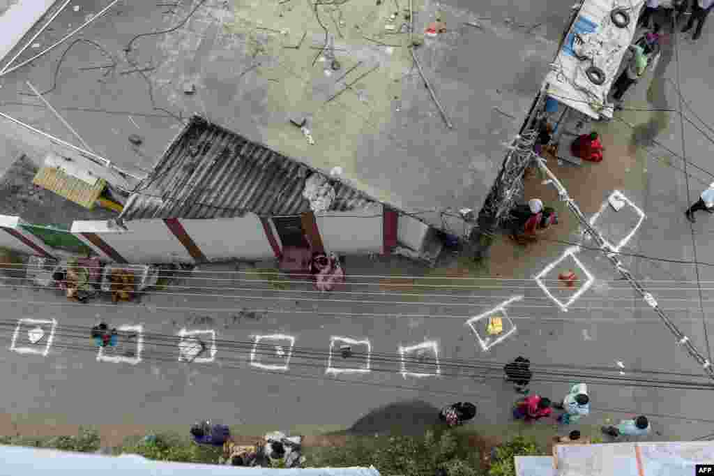 People keep their bags inside marked areas on a street as they wait to receive free rice distributed at a government store during a nationwide lockdown to prevent the spread of the coronavirus, in Hyderabad, India.