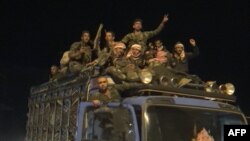 In this image grab from AFP footage, a convoy of Syrian regime troops arrives in the northern border town of Kobane (also known in Arabic as Ain Arab), Oct. 24, 2019.