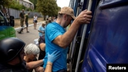 Volunteers assist a man to enter an evacuation train as Russian forces advance across the frontlines in the Donetsk region, at the train station in Pokrovsk, Ukraine, on Aug. 2, 2024.