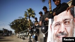 Policemen stand guard near a poster outside the constitutional court put up by supporters of Egyptian President Mohamed Morsi as they stage a sit-in, in Cairo, December 23, 2012. 