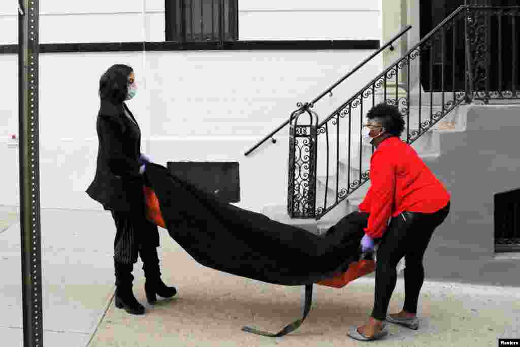  Manager Alisha Narvaez and resident funeral director Nicole Warring of International Funeral &amp; Cremation Services in Harlem, carry a deceased person into the basement area, during the COVID-19 outbreak, in Manhattan, New York City, April 2, 2020.