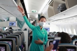 FILE - A flight attendant gives instructions to passengers on a plane in Ho Chi Minh City, Vietnam, March 16, 2020.