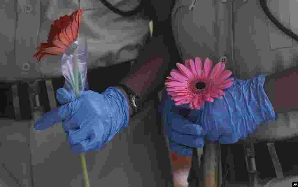 Security officers hold flowers given to them as a gesture of gratitude at the end of a free medical camp in Dharavi, one of Asia&#39;s biggest slums, in Mumbai, India.