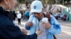 FILE - A man who only gave his first name as Ariel, of Honduras, receives an image of Saint Jude from a woman before crossing into the United States to begin his asylum case after being returned to Mexico, March 19, 2019, in Tijuana, Mexico.