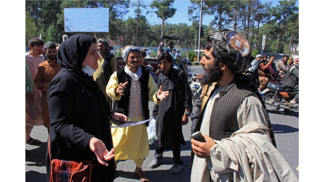 FILE - An Afghan woman protester (3L) speaks with a member (R) of the Taliban during a protest in Herat on Sept. 2, 2021.