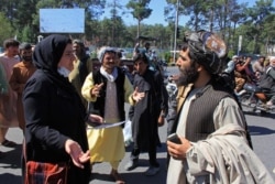 FILE - An Afghan woman protester (3L) speaks with a member (R) of the Taliban during a protest in Herat on Sept. 2, 2021.